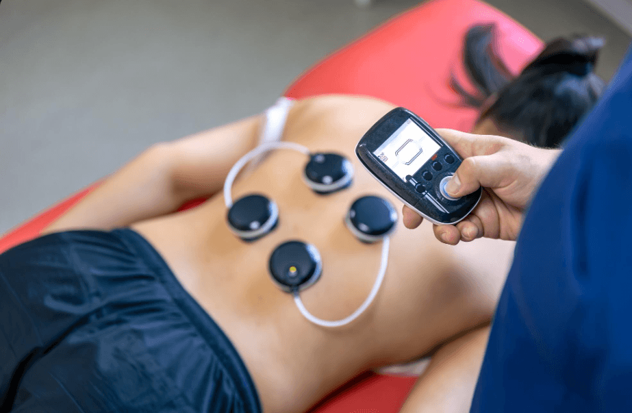 Electrode pads on a patient's back connected to a handheld stimulation unit