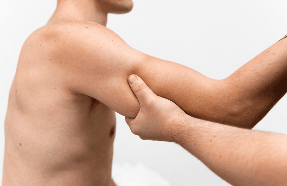 A therapist holds a patient's upper arm to work on the shoulder and arm muscles