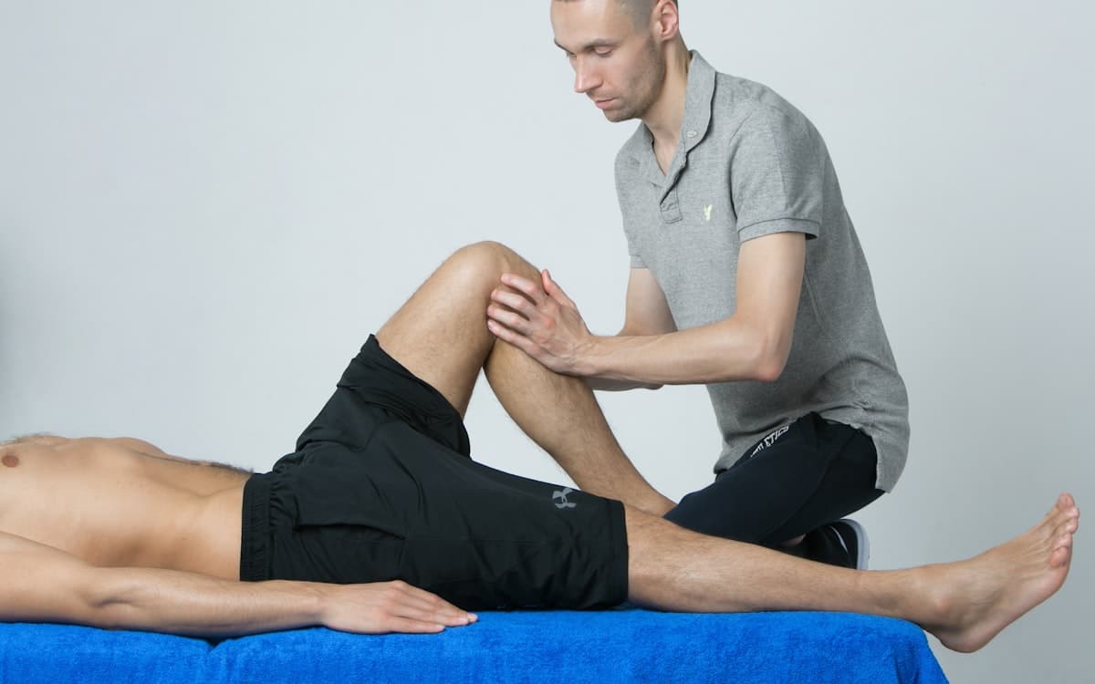 A therapist stretching a patient's leg on a treatment table during accident rehab