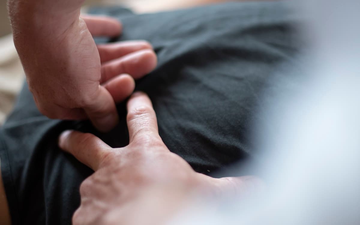 A clinician examines a tender area in a patient's upper back.