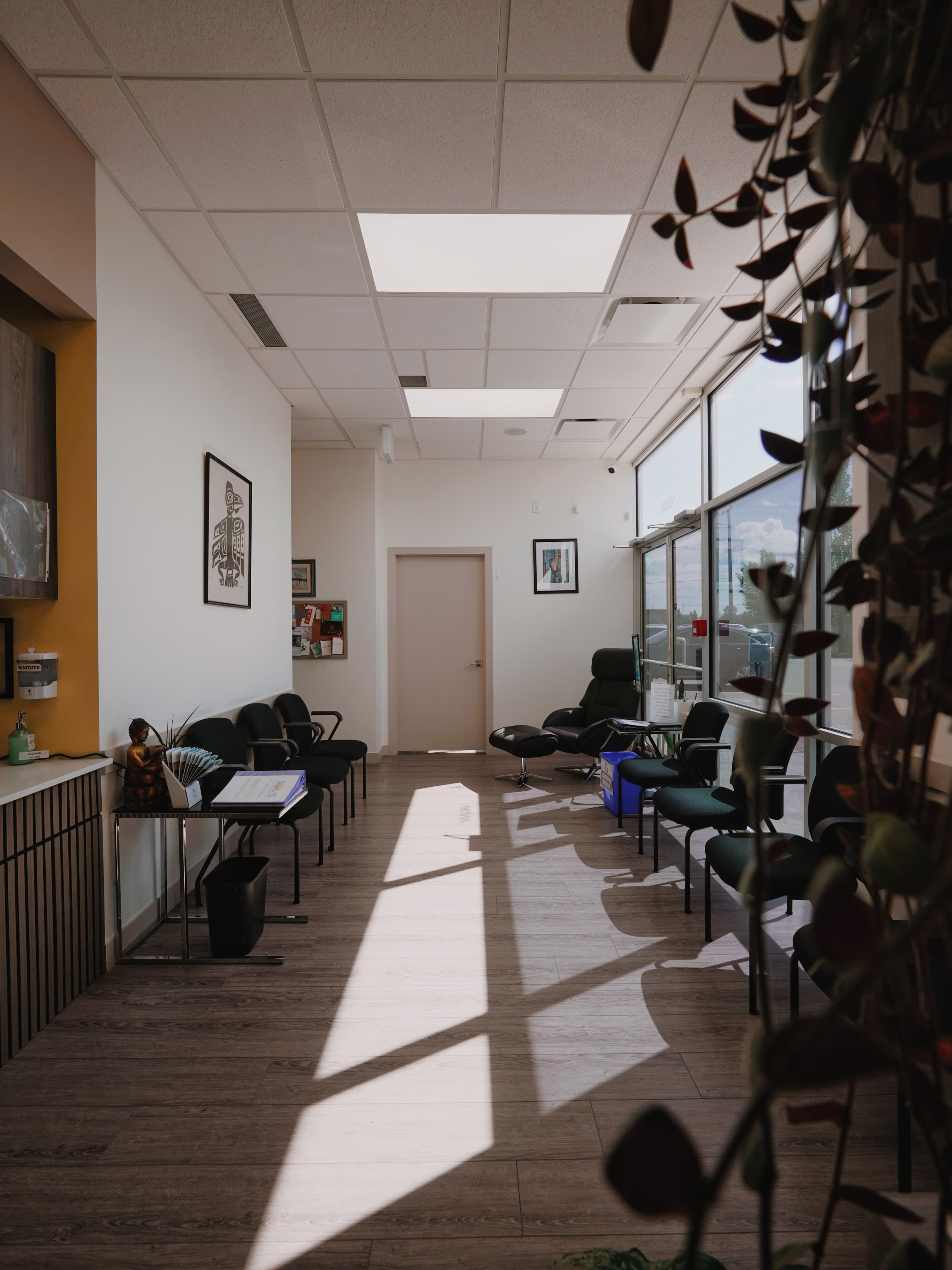 The sunlit waiting room at Solis Medical Clinic in West Edmonton, with seating along the window and a recliner by the infusion area.
