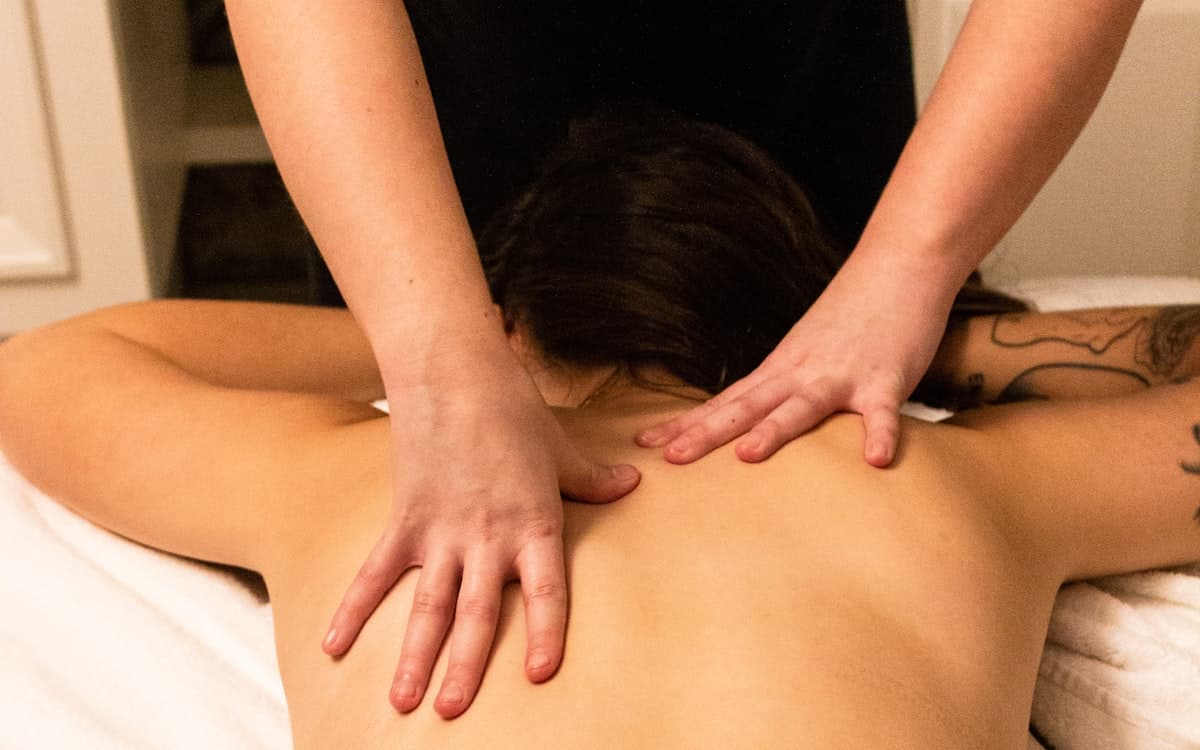 A massage therapist working along a patient's upper back