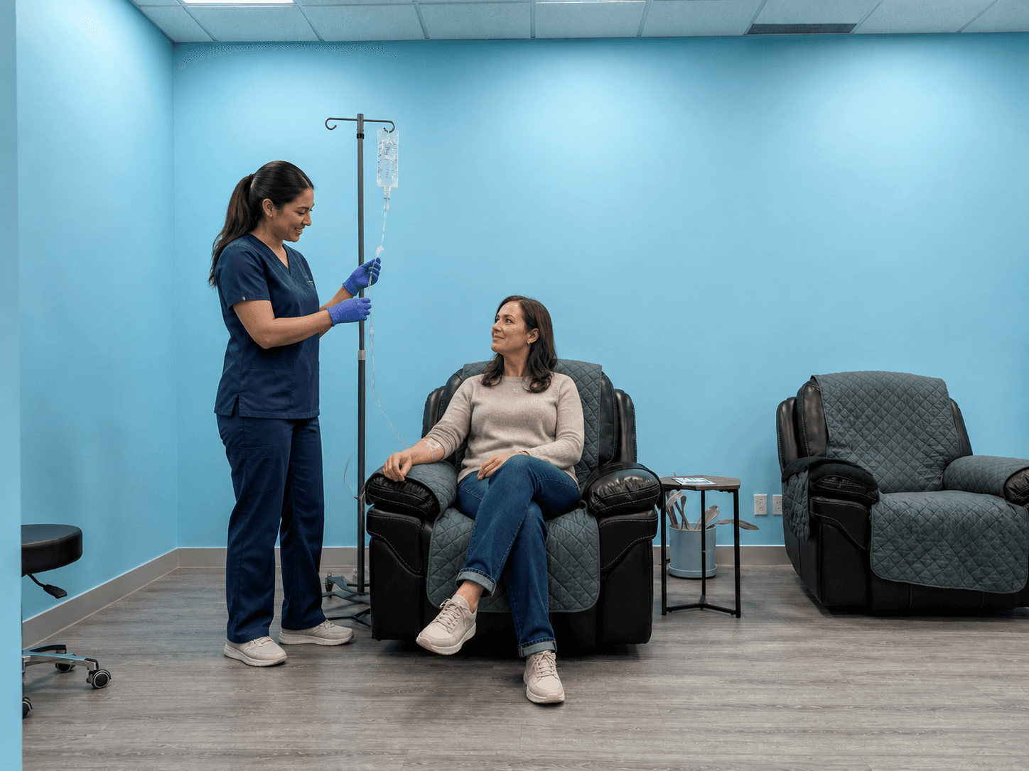 A nurse checking an IV infusion beside a patient seated in the Solis Medical Clinic infusion room in Edmonton